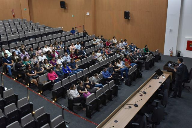 Tomada aérea de auditório, focando o público na audiência de palestra