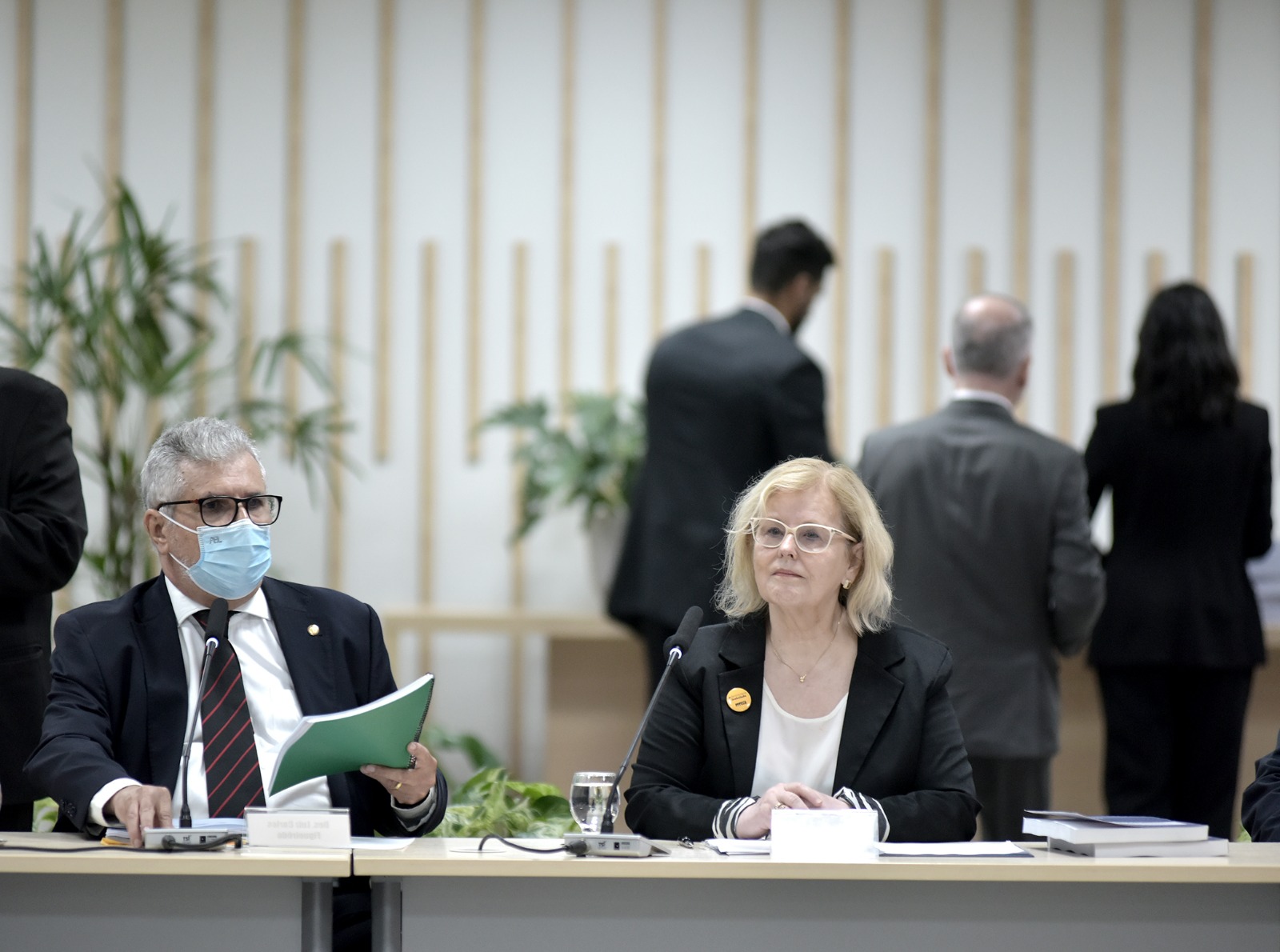 Foto mostra um homem e uma mulher, sentados à mesa, lado a lado.