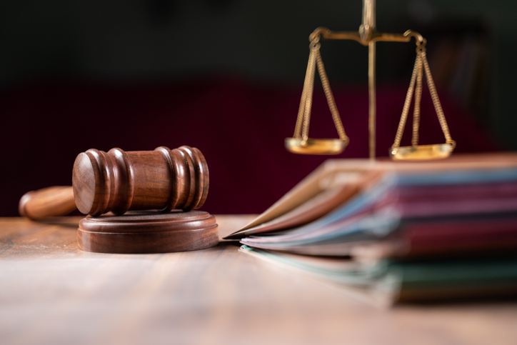 Fotografia de um martelo judicial e de uma balança sobre uma mesa