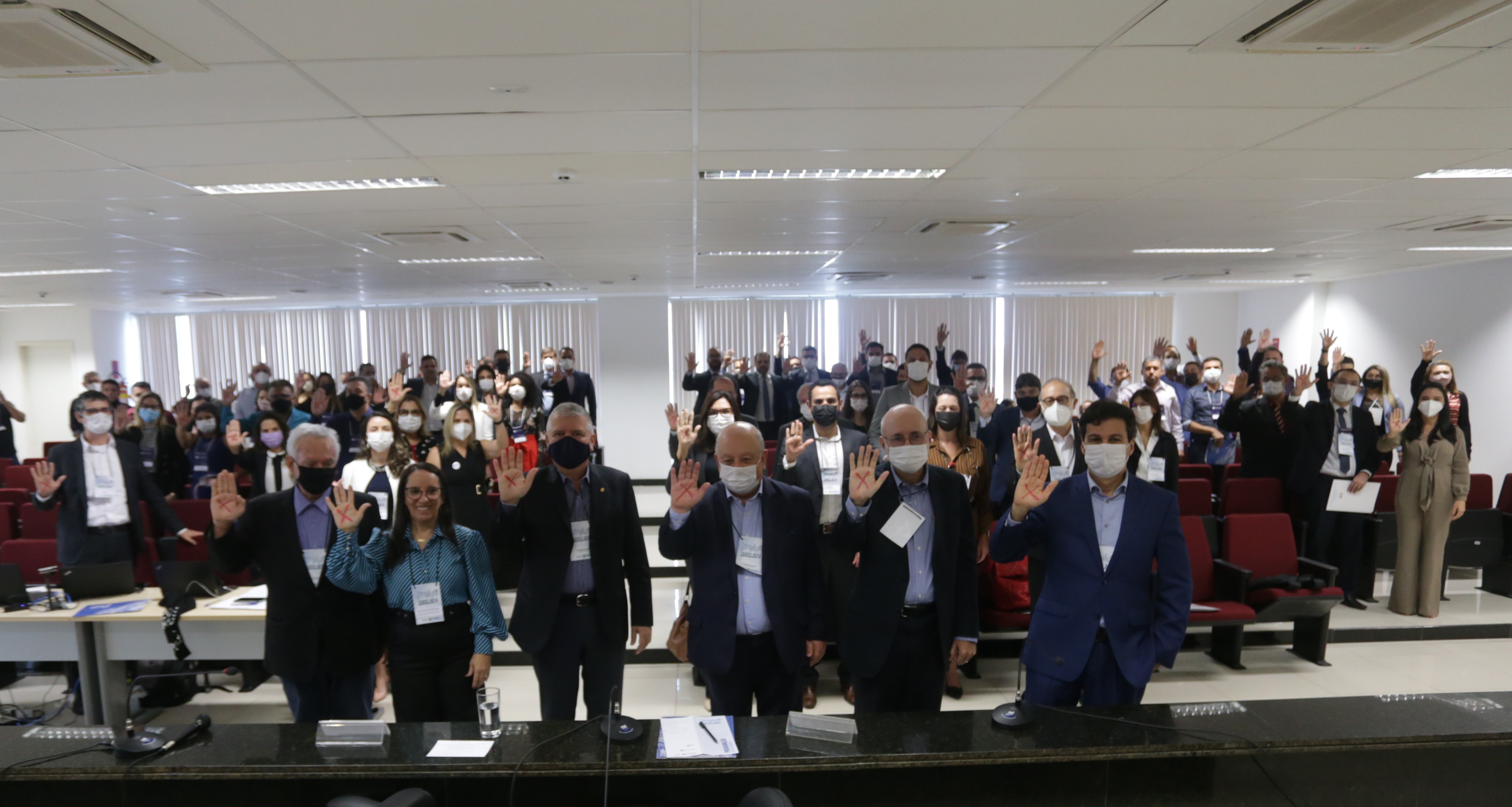 Todos os participantes do encontro com as mãos levantadas e um X vermelho