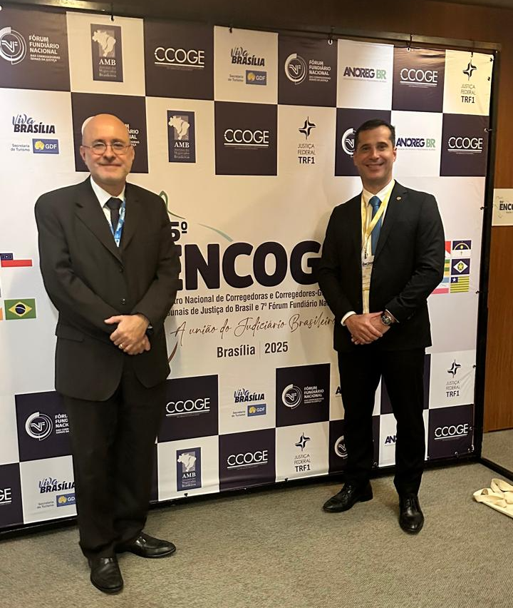 Corregedor pernambucano e seu juiz assessor em frente ao banner do Encoge 2025