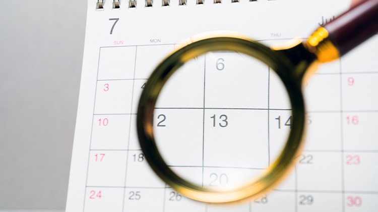 Um calendário com uma lupa na frente focando na data 13